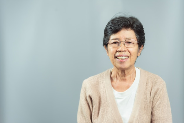 Retrato de mulher velha sorridente feliz em cinza