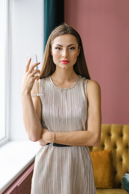 Retrato de mulher vestida com um vestido prateado e segurando uma taça de champanhe