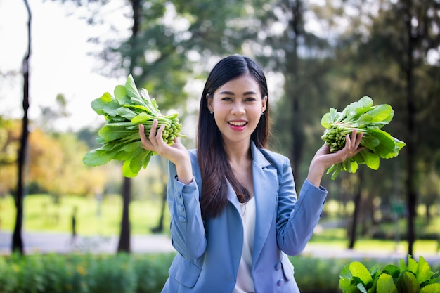 Retrato de mulheres segurando vegetais na plantação orgânica e verificação do cultivo de plantas