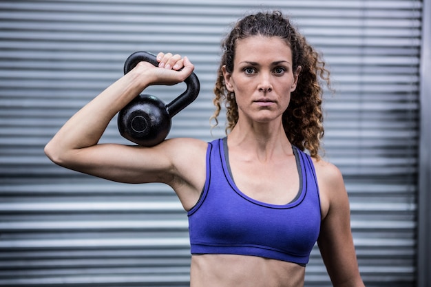 Retrato, de, muscular, mulher, exercitar, com, kettlebell, em, crossfit, ginásio