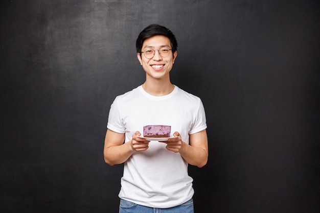 Retrato de namorado asiático bonito carinho alegre trazer pedaço de bolo saboroso