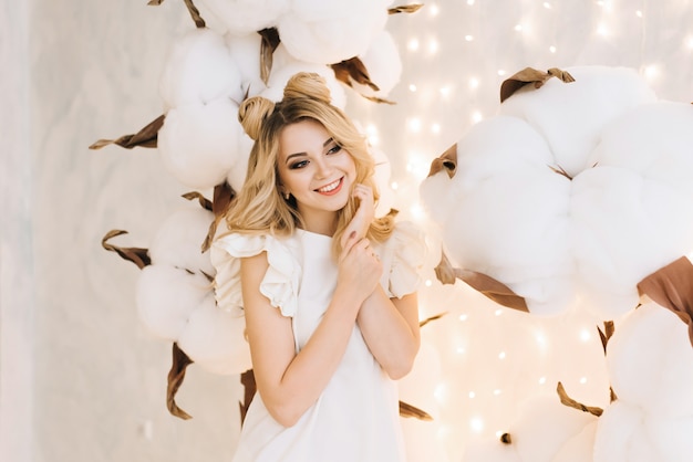 Retrato de Natal de uma linda garota com cabelos brancos. Uma mulher atraente entre os grandes ramos do algodão