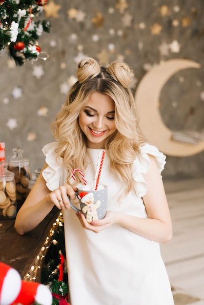 Retrato de Natal de uma menina bonita com uma caneca vermelha em uma barra de Natal. Ano novo e conceito de Natal