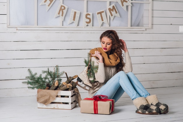 Retrato de Natal de uma menina com presente em roupas de inverno.