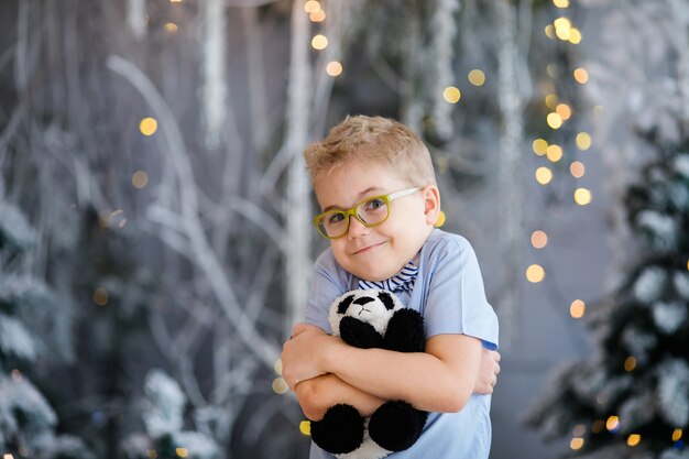 Foto retrato de natal do menino criança feliz com grandes óculos, segurando o estúdio interior de urso de brinquedo