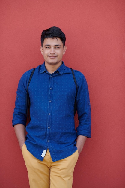 retrato de negócios de inicialização do empresário indiano casual com uma camisa azul e mochila na frente da parede rosa