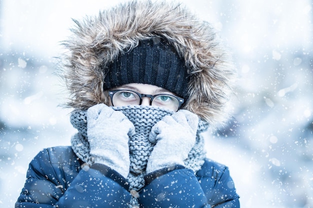 Retrato de neve de inverno de uma menina em roupas quentes