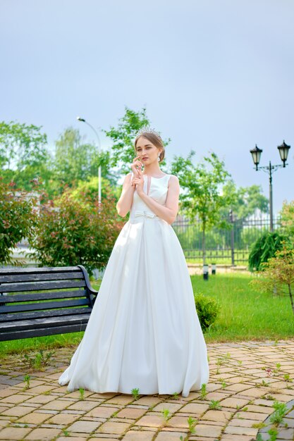 Retrato de noiva bonita com coroa no cabelo ao ar livre perto de pavilhão de cerimônia
