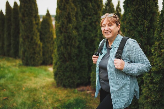 Retrato de outddor de aposentado feminino europeu feliz com mochila apreciando a bela natureza enquanto caminhada nórdica Pessoas envelhecidas estilo de vida ativo e conceito de saúde