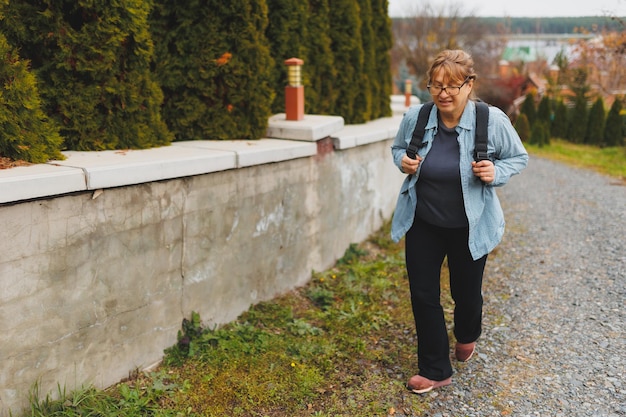 Retrato de outddor de aposentado feminino europeu feliz com mochila apreciando a bela natureza enquanto caminhada nórdica Pessoas envelhecidas estilo de vida ativo e conceito de saúde