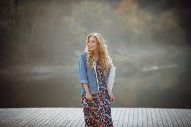 Retrato de outono ao ar livre de menina com chapéu e jeans. Plano de fundo natural, paisagem rural, estilo country perto de um lago na floresta