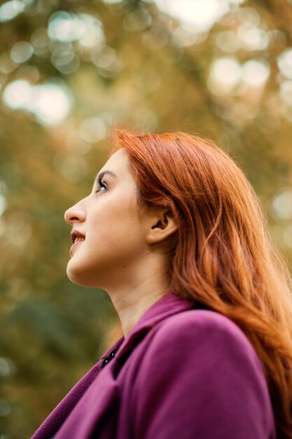 Foto retrato de outono de uma linda garota ruiva sincera com folhas de outono no cabelo