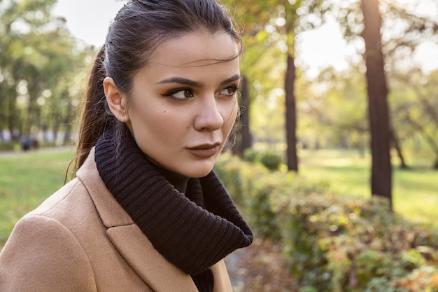Retrato de outono de uma morena com um casaco close up parque oktyabrsky