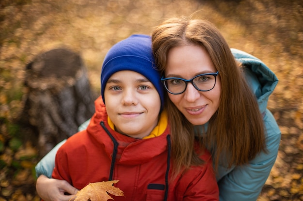 Retrato de outono de uma mulher bonita e feliz com seu filho em um fundo de natureza outono