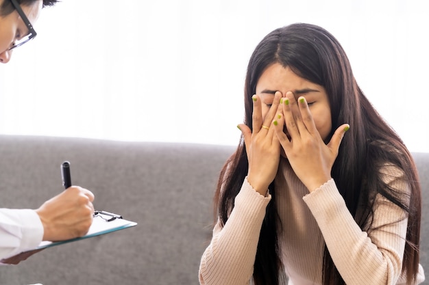 Retrato de paciente asiática com máscara facial conversando com um médico psicoterapeuta