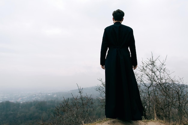 Retrato de padre ou pastor católico bonito barbudo posando ao ar livre nas montanhas x9