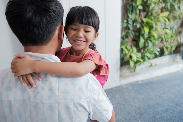 Retrato de pai asiático abraçando a filha antes de ir para a escola pela manhã