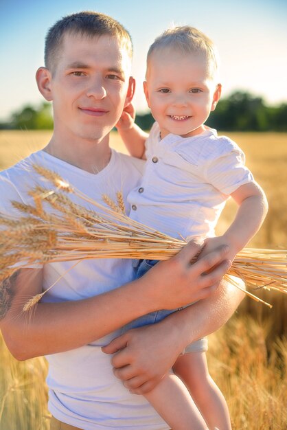 retrato de pai com filho pequeno no campo de trigo de verão