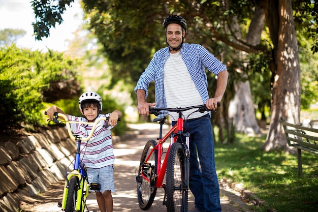 Retrato de pai e filho em pé com bicicleta no parque