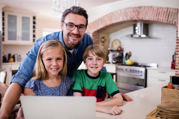 Retrato de pai e filhos usando o laptop na cozinha