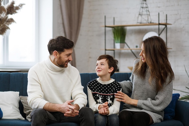 Retrato de pai, mãe e filho sorrindo. Família feliz, passando algum tempo juntos em casa. Menino bonito com a mãe e o pai brincando em casa. Tempo para o lazer em família. Valores de família.