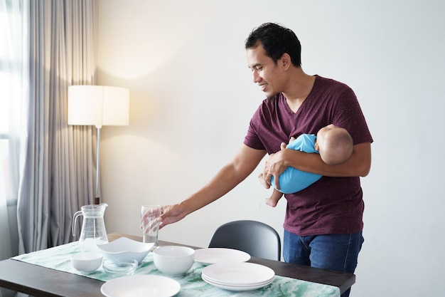 Retrato de pai solteiro fazendo tarefas domésticas enquanto carrega seu filho