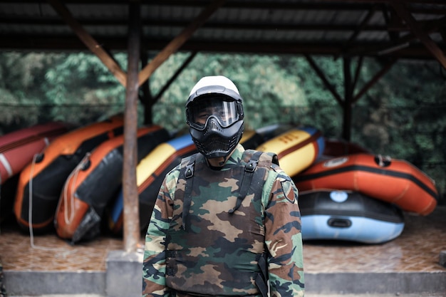 Retrato de paintballer masculino em uniforme e máscaras protetoras se preparando antes do jogo de paintball ou