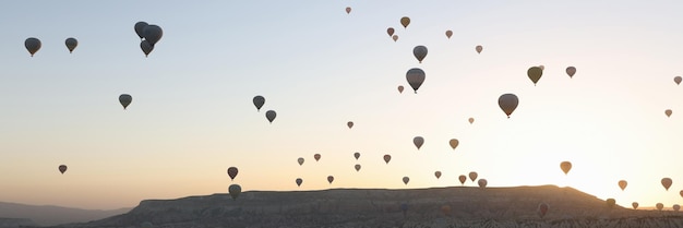 Retrato de paisagem panorâmica com balões de ar quente, nascer do sol e montanhas ao fundo