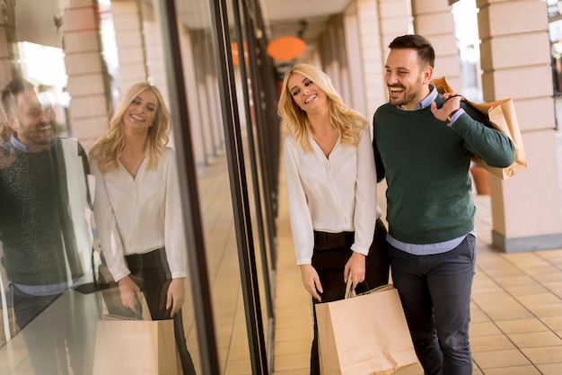 Retrato, de, par jovem, com, bolsas para compras, em, cidade