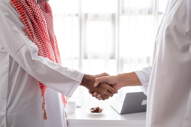 Retrato de parceiro muçulmano de negócios apertando a mão na reunião
