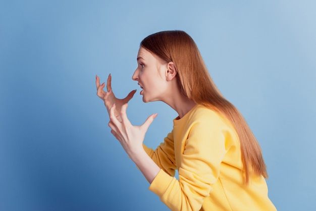 Retrato de perfil de senhora irritada com raiva, olhar para o espaço vazio, levantar as mãos conceito de pms sobre fundo azul