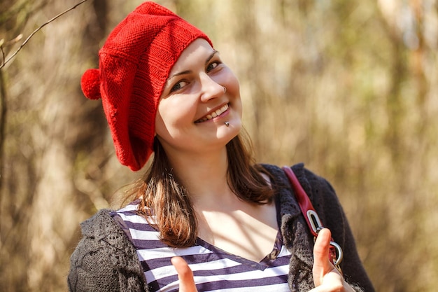 Retrato de perto ao ar livre de uma jovem linda e feliz sorridente usando boina de malha vermelha estilo francês