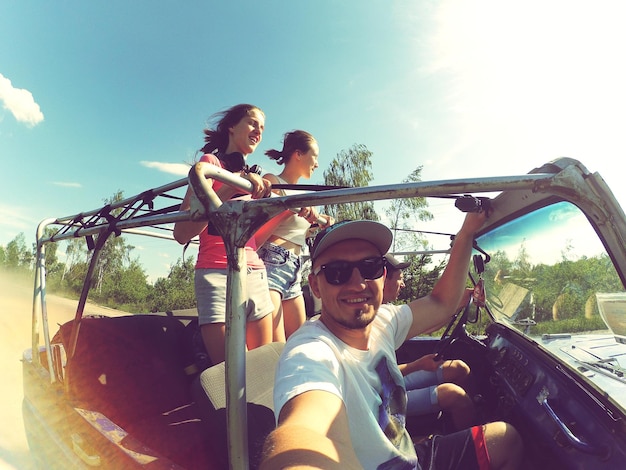 Retrato de pessoas felizes em um carro contra o céu