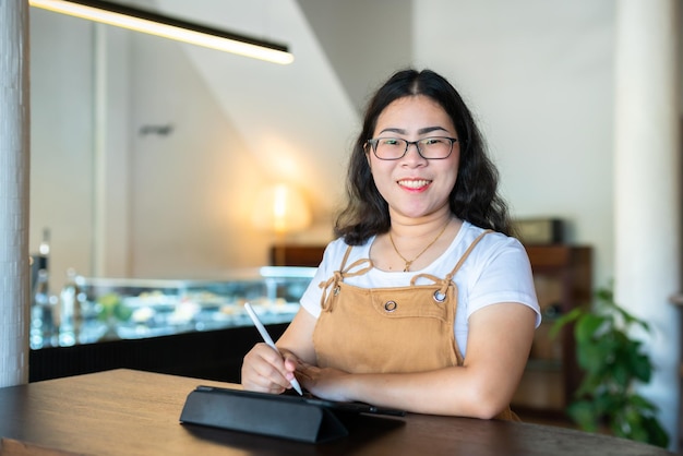 Retrato de pessoas freelance asiáticas de negócios feminino usando óculos elegante hipste desenhe ou tome nota no tablet digital com caneta eletrônica para navegar na internet conversando e blogando no café