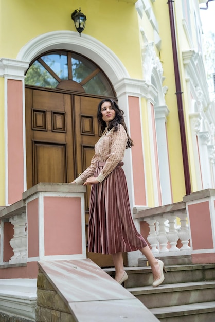 Retrato de poses de mulher bonita perto do prédio da cidade