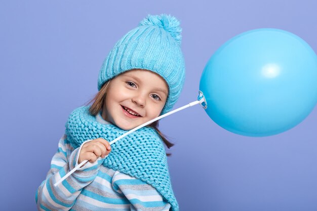 Retrato de positivo pacífico garoto bonitinho segurando balão azul com uma mão