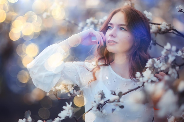 retrato de primavera de uma mulher adulta feliz em um jardim florescendo, raios solares e brilho, menina de flores de abril