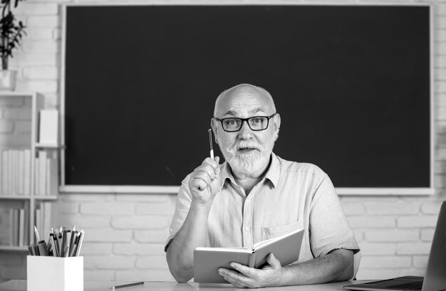 Retrato de professor sênior ensinando linha de alunos do ensino médio com caderno na sala de aula em