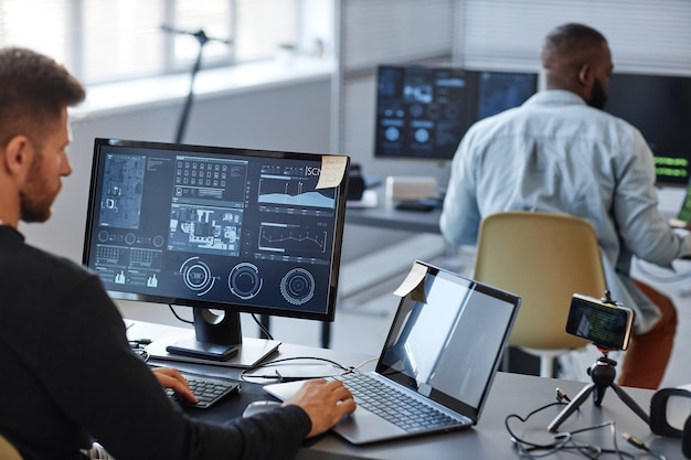 Retrato de programador masculino ou especialista em dados usando computador no escritório com gráficos na cópia da tela