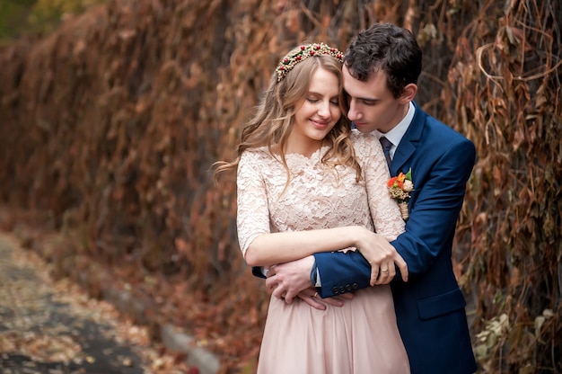 Retrato de recém-casados felizes na natureza outono. noiva e noivo abraçando e beijando.