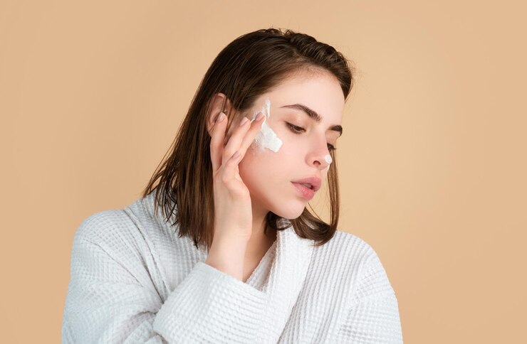 Foto retrato de rosto de beleza de mulher de linda modelo feminina aplicando creme hidratante em seu rosto bonito cuidados com a pele e conceito de tratamento facial de spa de pele saudável
