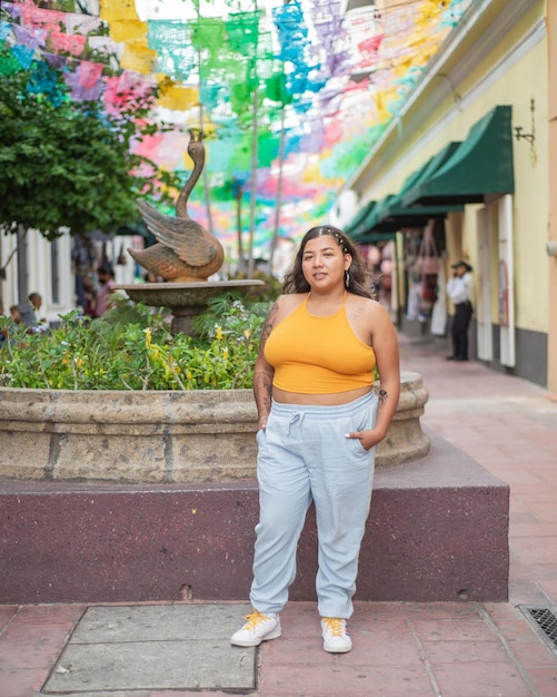 Retrato de rua de jovem olhando para a câmera com bandeiras multicoloridas no fundo.