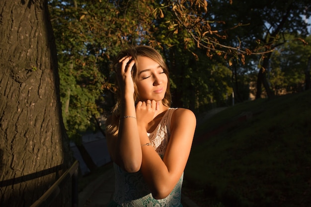 Retrato de rua de uma jovem e adorável modelo com os olhos fechados, posando em um dia de sol