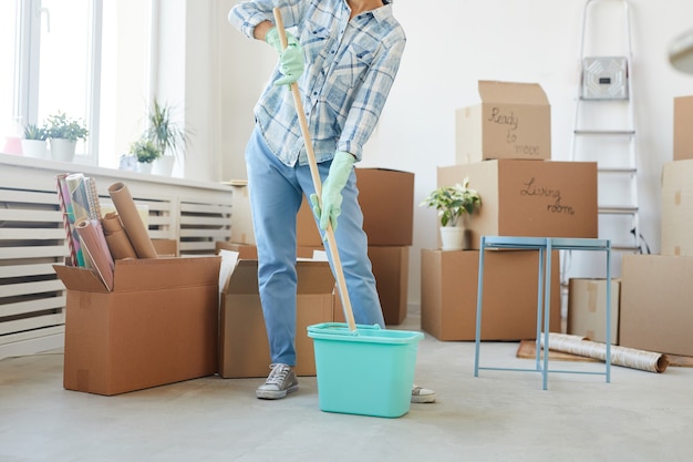 Retrato de seção inferior de uma jovem feliz limpando uma casa ou apartamento novo enquanto se muda