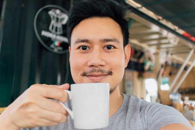 Retrato de Selfie da caneca feliz da bebida do homem de café quente.