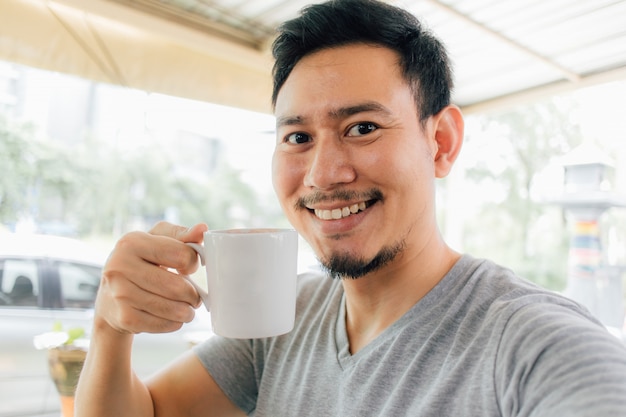 Retrato de Selfie da caneca feliz da bebida do homem de café quente.