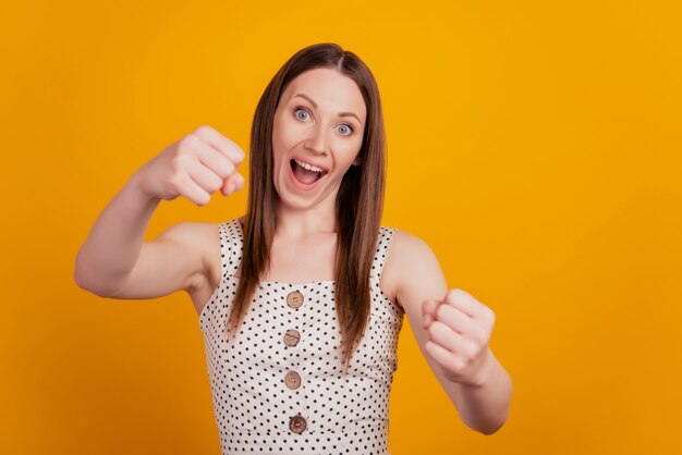 Retrato de senhora adorável positiva segurando o volante invisível sobre fundo amarelo