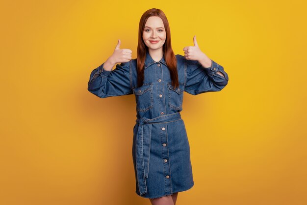 Retrato de senhora confiável promotora positiva levantando dois polegares sobre fundo amarelo