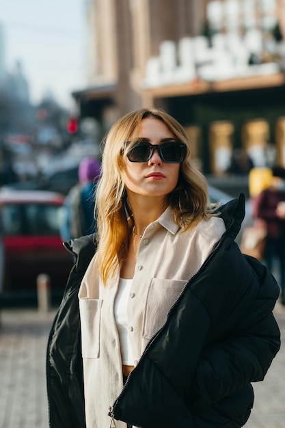 retrato de senhora elegante em roupas casuais e óculos de sol andando na rua na semana de moda