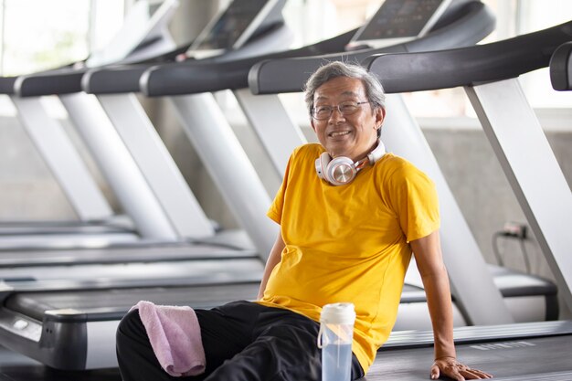 Retrato de sênior com óculos, fazendo exercícios no ginásio de fitness.